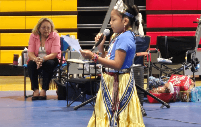 Crowned Myamee speaks to the crowd holding a microphone