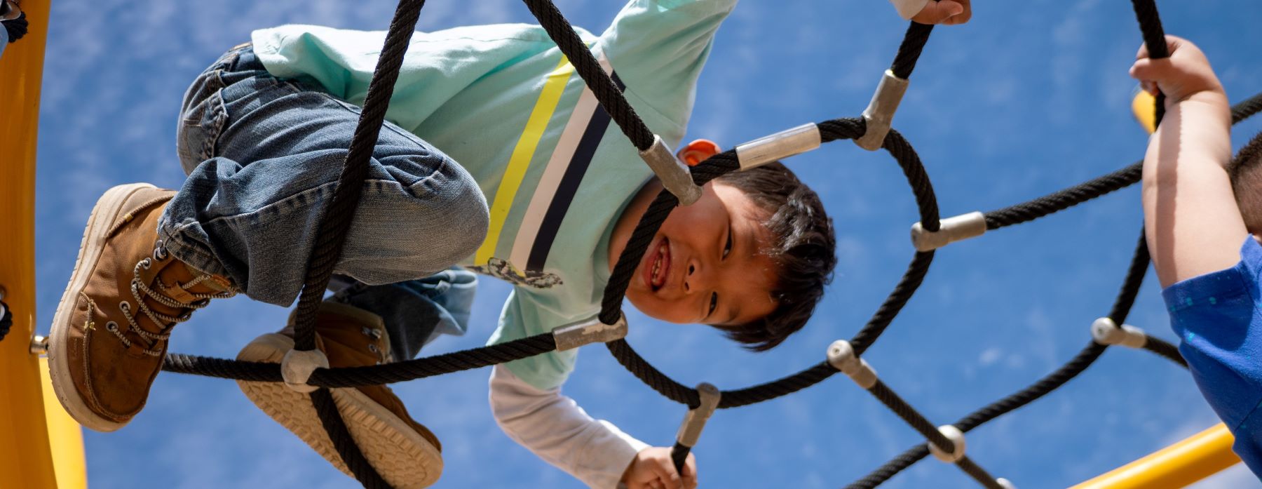 Student playing happily on playground equipment.