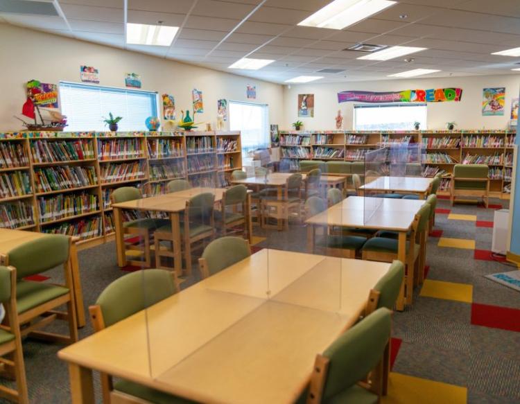 school library with rows of bookshelves, tables, and chairs
